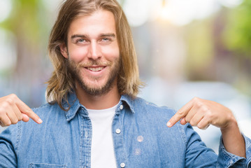 Young handsome man with long hair over isolated background looking confident with smile on face,...