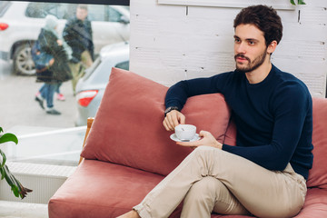 handsome stylish man sitting on the red sofa. close up photo. free time. lifestyle