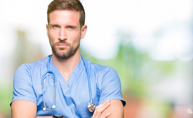 Handsome doctor man wearing medical uniform over isolated background skeptic and nervous,...