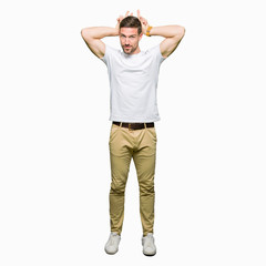 Handsome man wearing casual white t-shirt Posing funny and crazy with fingers on head as bunny ears, smiling cheerful