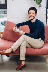 cheerful awesome good looking man with coffee is looking at the camera. close up photo. guy is resting after work