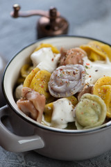 Close-up of boiled multicolored meat dumplings or pelmeni in a grey pot, selective focus