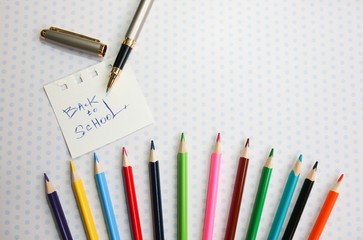 Color pencils lying on cute spotted background with dots. Back to school concept and sign written with a pen. Colorful art studying and painting process. Copy space place for postcard wish.