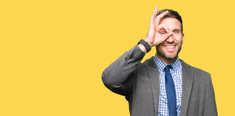Naklejka premium Handsome business man wearing suit and tie doing ok gesture with hand smiling, eye looking through fingers with happy face.