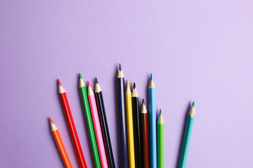 Fototapeta premium Color pencils lying on pastel purple background. Back to school concept. Colorful art studying and painting process. Drawing with pencils. Copy space place for postcard wish.