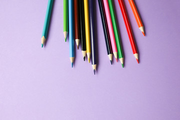 Color pencils lying on pastel purple background. Back to school concept. Colorful art studying and painting process. Drawing with pencils. Copy space place for postcard wish.