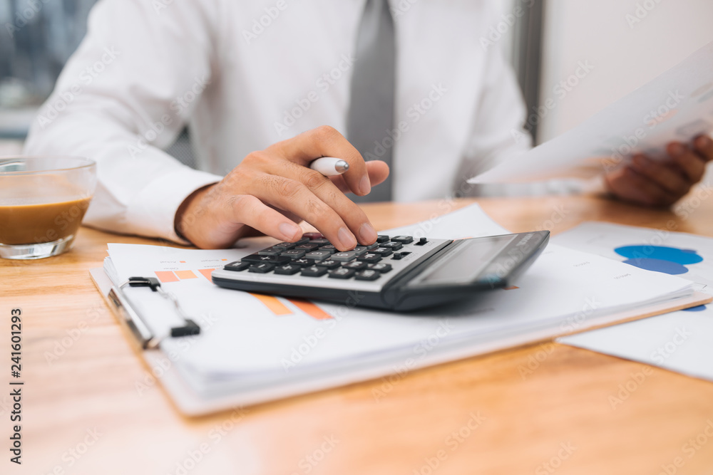 Poster partial view of businessman with calculator working at workplace with documents and laptop