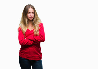 Young beautiful blonde woman wearing red sweater over isolated background skeptic and nervous, disapproving expression on face with crossed arms. Negative person.