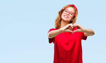 Young beautiful woman over isolated background smiling in love showing heart symbol and shape with hands. Romantic concept.