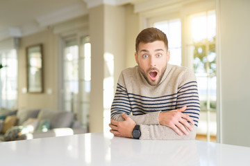 Young handsome man at home afraid and shocked with surprise expression, fear and excited face.
