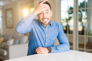 Young handsome man at home stressed with hand on head, shocked with shame and surprise face, angry and frustrated. Fear and upset for mistake.