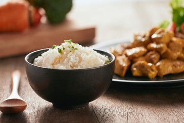 White rice with curry and chicken in black plate on wooden table