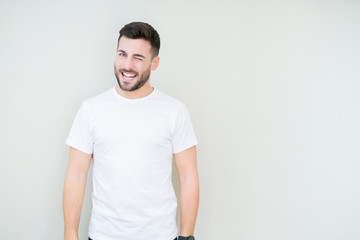 Young handsome man wearing casual white t-shirt over isolated background winking looking at the camera with sexy expression, cheerful and happy face.