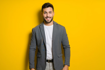 Young handsome man possing and modeling over yellow isolated background