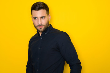 Fototapeta premium Young handsome man possing and modeling over yellow isolated background