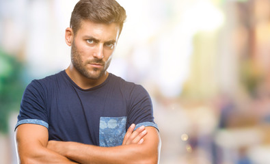 Fototapeta premium Young handsome man over isolated background skeptic and nervous, disapproving expression on face with crossed arms. Negative person.