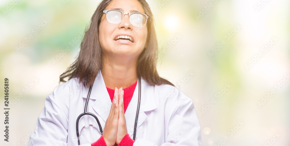 Sticker Young arab doctor woman over isolated background begging and praying with hands together with hope expression on face very emotional and worried. Asking for forgiveness. Religion concept.