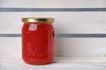 Red caviar in big glass jar on white shelf