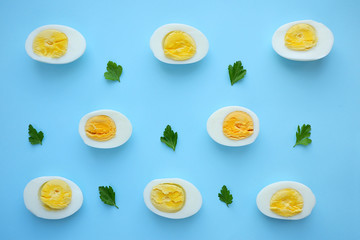 Pattern of boiled eggs and parsley on a blue background. Easter template, top view