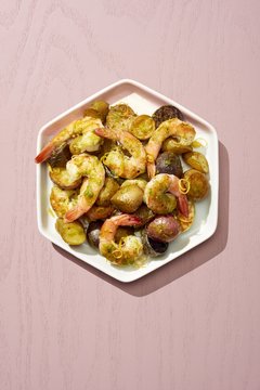 Prawns and vegetable served on plate isolated on pink background