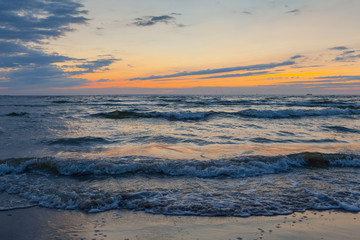 Fototapeta premium Low waves on Baltic sea at sunset. Cosy flat sandy beach.
