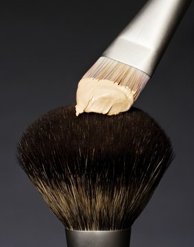 Close Up Of Makeup Brush And Cream Against Black Background