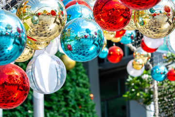 Shiny xmas glass baubles ball hanging on fir over colorful bokeh with festive. Christmas bauble twinkling light and ornament on colurful glitter.Merry Christmas and Happy New Year background.