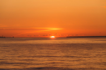 Fototapeta premium Colourful orange sunset with bright clear sky over Baltic sea.