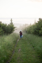 Naklejka na ściany i meble single girl meets sunrise in a misty morning in a field in summer