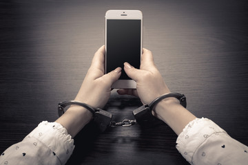 handcuffed hands with a mobile phone