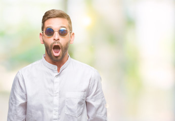 Young handsome man wearing glasses over isolated background afraid and shocked with surprise...