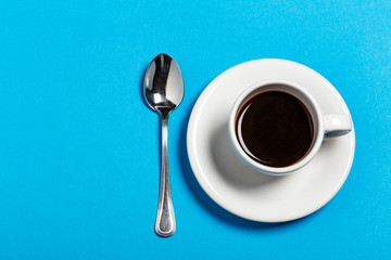 Tazza di caffè con cucchiaino su sfondo azzurro
