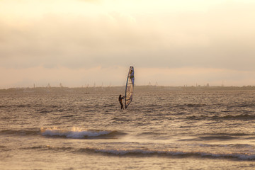 TALLINN, ESTONIA - AUGUST, 10, 2017: Sportman windsurfer on the sea surface against sunset orange sky