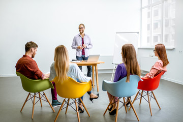Young man as a speaker reporting to the audience during the meeting in the conference room with...