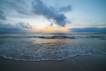 Calm Baltic sea at sunset with beautiful clouds and low waves