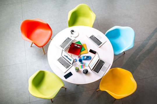 Top view on the working place with round table and colorful chairs in the office