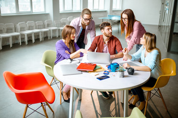 Group of a young coworkers dressed casually working together with laptops in the modern office