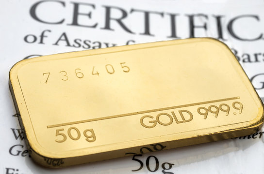 Minted gold bar weighing 50 grams fineness 999.9 on the background of the certificate.