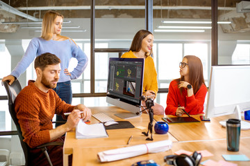Group of a young coworkers dressed casually modeling 3d project working on computers in the modern office