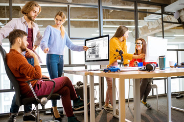 Group of a young coworkers working together on architectural project with computers in the modern...