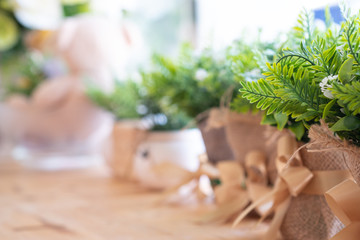 Small plastic flower and leaves of inflorescences are decorated with blurred background with copy space. Decorate green leaf in a cafe interior.