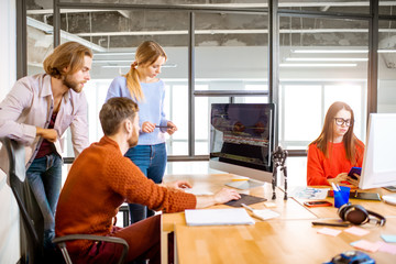 Team of a young programmers dressed casually working on computer code sitting in the modern office...