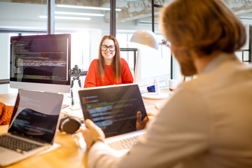 Team of a young programmers dressed casually working on computer code sitting in the modern office...