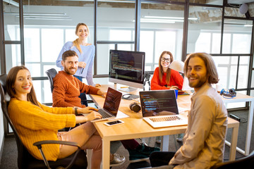 Portrait of a group of young programmers dressed casually working on computer code sitting in the modern office interior