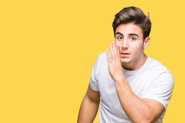Young handsome man wearing white t-shirt over isolated background hand on mouth telling secret...