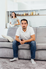 A man watches TV, while his wife looks at him