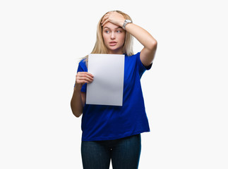 Young caucasian woman holding blank paper sheet over isolated background stressed with hand on head, shocked with shame and surprise face, angry and frustrated. Fear and upset for mistake.
