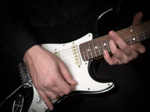Guitarist hands playing on electric guitar, close up, selected focus
