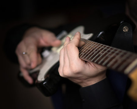 Male hands playing on electric guitar, close up, selected focus