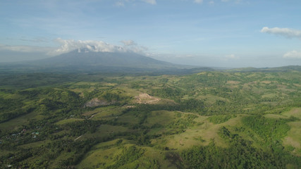 Fototapeta premium Aerial view of mountain valley with hillscovered forest, trees, mount Iriga. Luzon, Philippines. Slopes of mountains with evergreen vegetation. Mountainous tropical landscape.